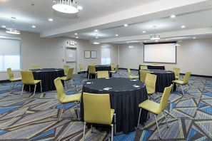 A conference room with multiple tables and chairs, a projector screen, and an exit sign. - Holiday Inn Express Arlington by IHG (Arlington)