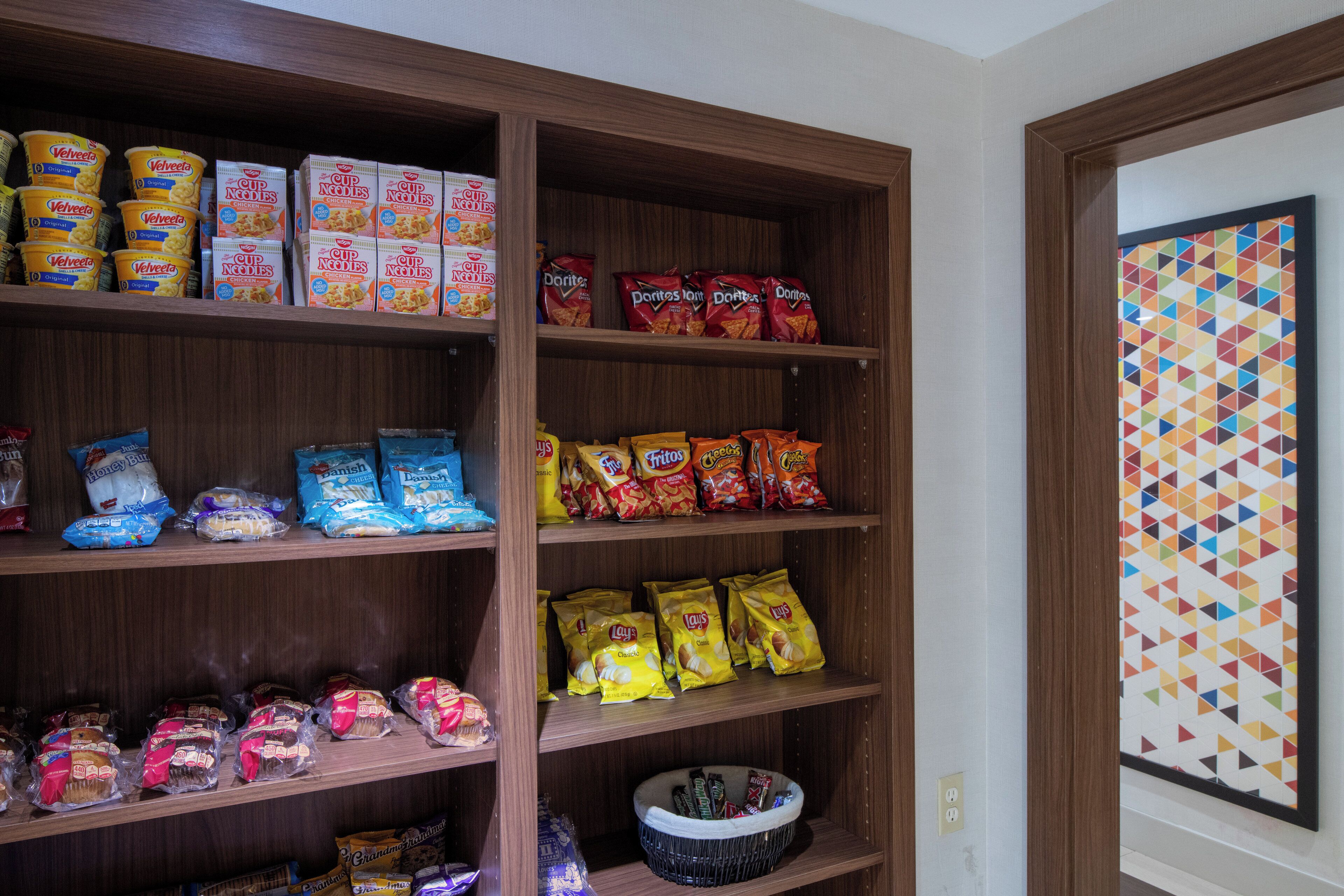 A pantry stocked with various food items including pasta, chips, and snacks.