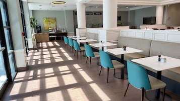 Un restaurante moderno con una barra larga, varias mesas y sillas.