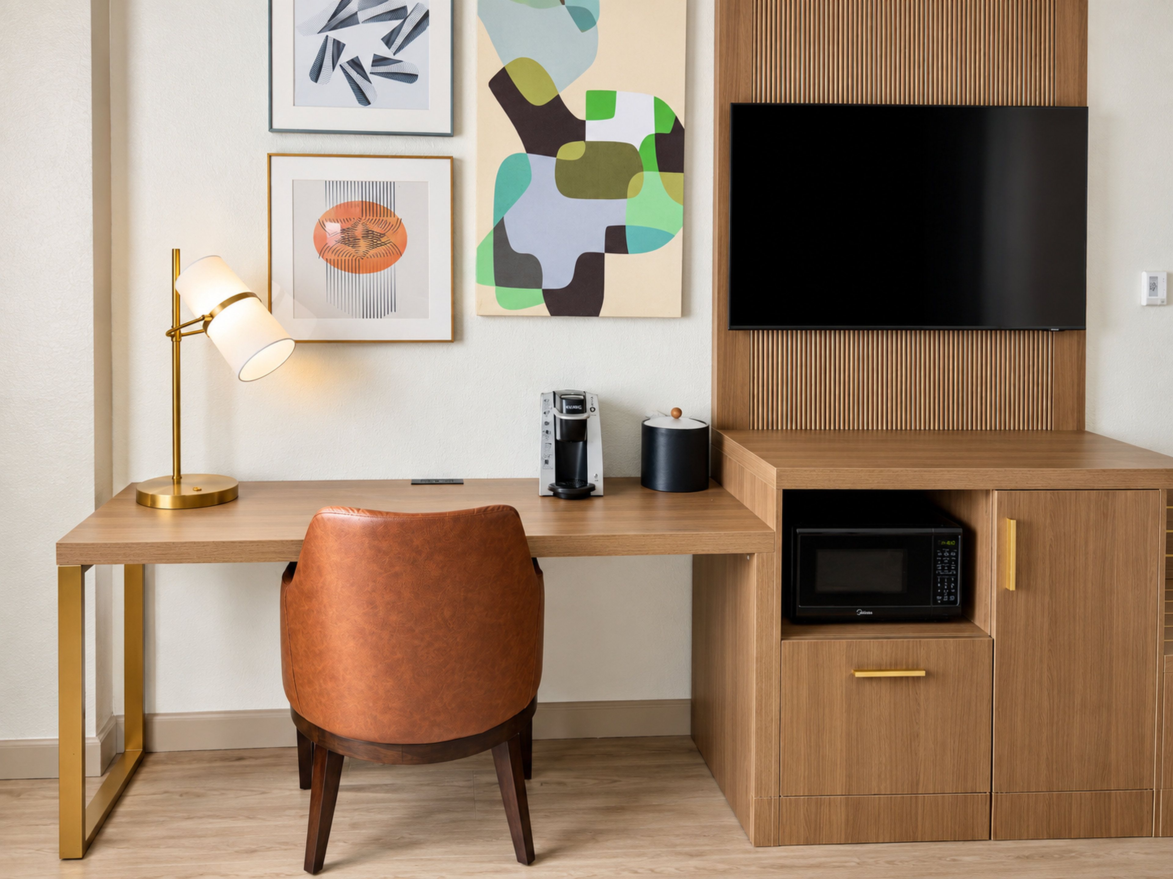 Una cocina moderna con encimera de madera, microondas negro, cafetera y televisor montado sobre la encimera.