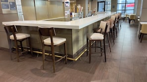 Un espace bar doté d’un long comptoir, de nombreux tabourets et d’un mini-bar.
