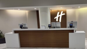 A reception desk with a wooden panel, two card readers, and a large illuminated 'H' sign.
