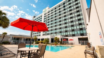 Un hotel con piscina, zona de estar al aire libre y fachada de edificio moderna.