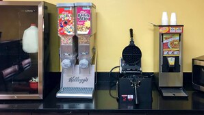 Uma máquina de café, um dispensador de leite e um aparelho de waffle em uma bancada.