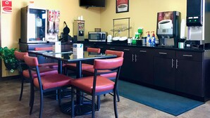 Um restaurante com balcão, cadeiras, televisão, micro-ondas e máquina de café.