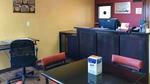 Uma área de recepção com balcão, computador e assentos.