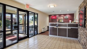 A hotel lobby with a reception desk, a clock, and an exit sign. - Red Roof Inn Shelbyville (Shelbyville)