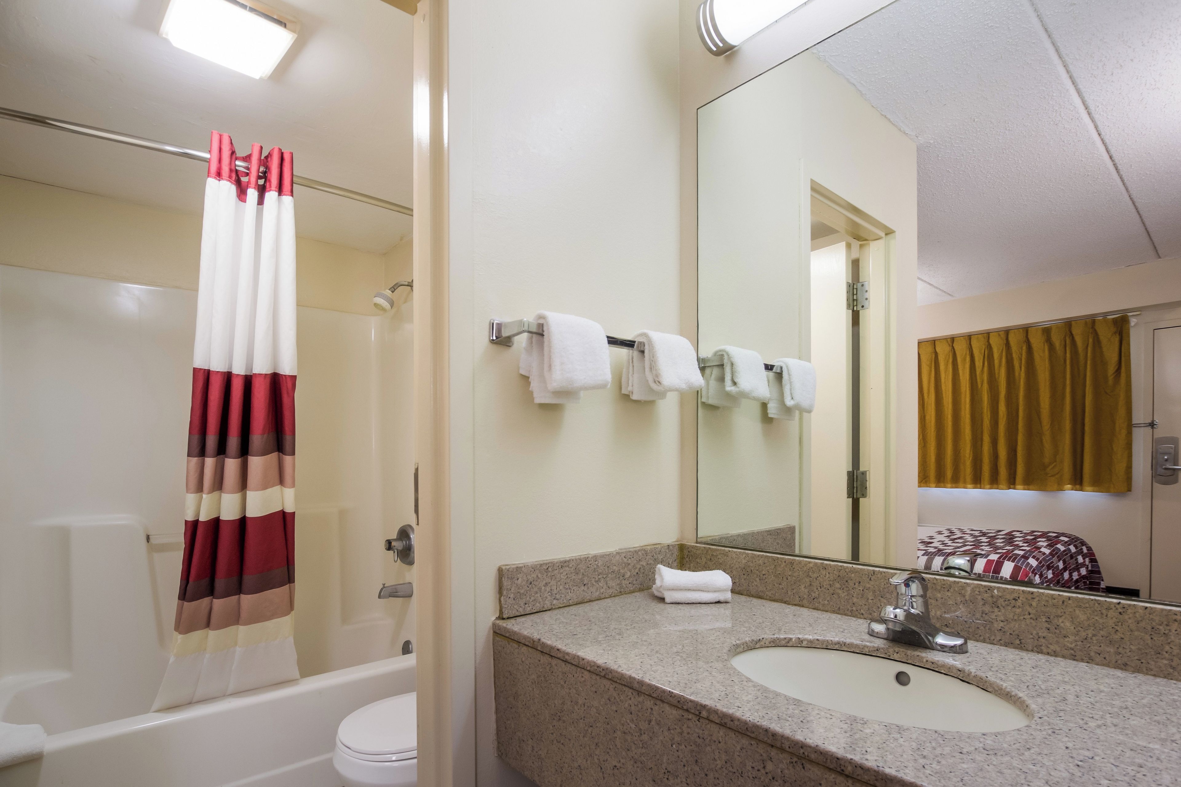 Un baño con bañera, inodoro, lavamanos y espejo.