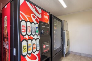 Máquina expendedora con diversas opciones de bebidas, incluyendo Coca-Cola y Sprite, y un refrigerador.
