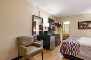 Une chambre d’hôtel équipée d’un lit, d’un bureau, d’une chaise, d’une télévision, d’un four à micro-ondes et d’un réfrigérateur.