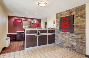 A hotel reception area with a digital clock, a 'Free Wi-Fi All Rooms' sign, and a 'Red Roof Inn' sign.