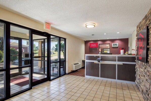 Un espace d’accueil avec une porte d’entrée en verre, une horloge et une enseigne Red Roof Inn.
