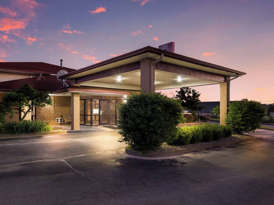 A hotel with a covered entrance, a satellite dish, and a well-lit driveway.