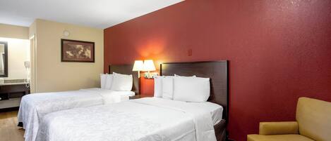 A hotel room with two beds, a chair, a lamp, and a painting on the wall.