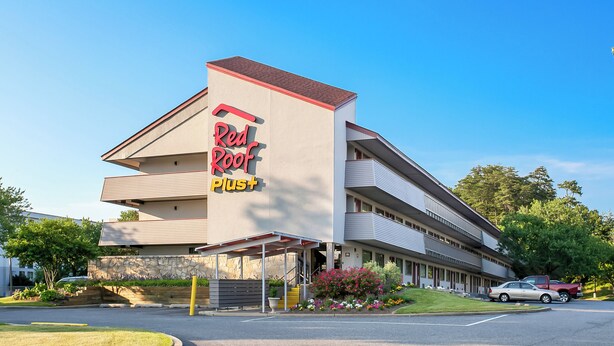Een Red Roof Plus hotel met een modern design, herkenbaar aan de opvallende signage en een overdekte ingang.