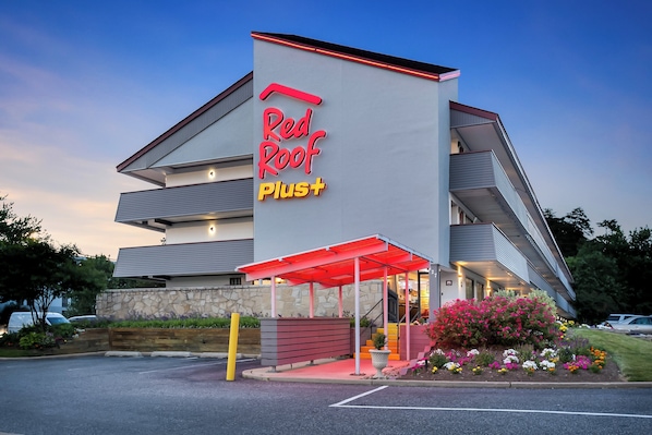 A Red Roof Plus hotel with a modern design, featuring a prominent entrance and a covered outdoor area.