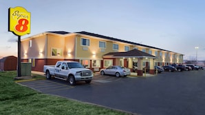 A Super 8 motel with a parking lot, a white pickup truck, and several cars parked in front. - Super 8 by Wyndham Lees Summit (Lee's Summit)