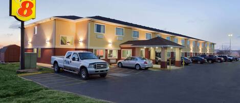 Un motel de type Super 8 avec un parking, un camionnette blanche et plusieurs voitures garées devant.