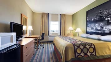 Ein Hotelzimmer mit Bett, Schreibtisch, Fernseher und einem großen Fenster mit Vorhängen.