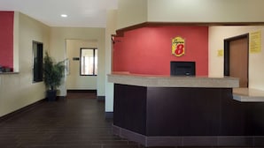A reception area with a counter, a potted plant, and a sign with the number 8. - Super 8 by Wyndham Lees Summit (Lee's Summit)