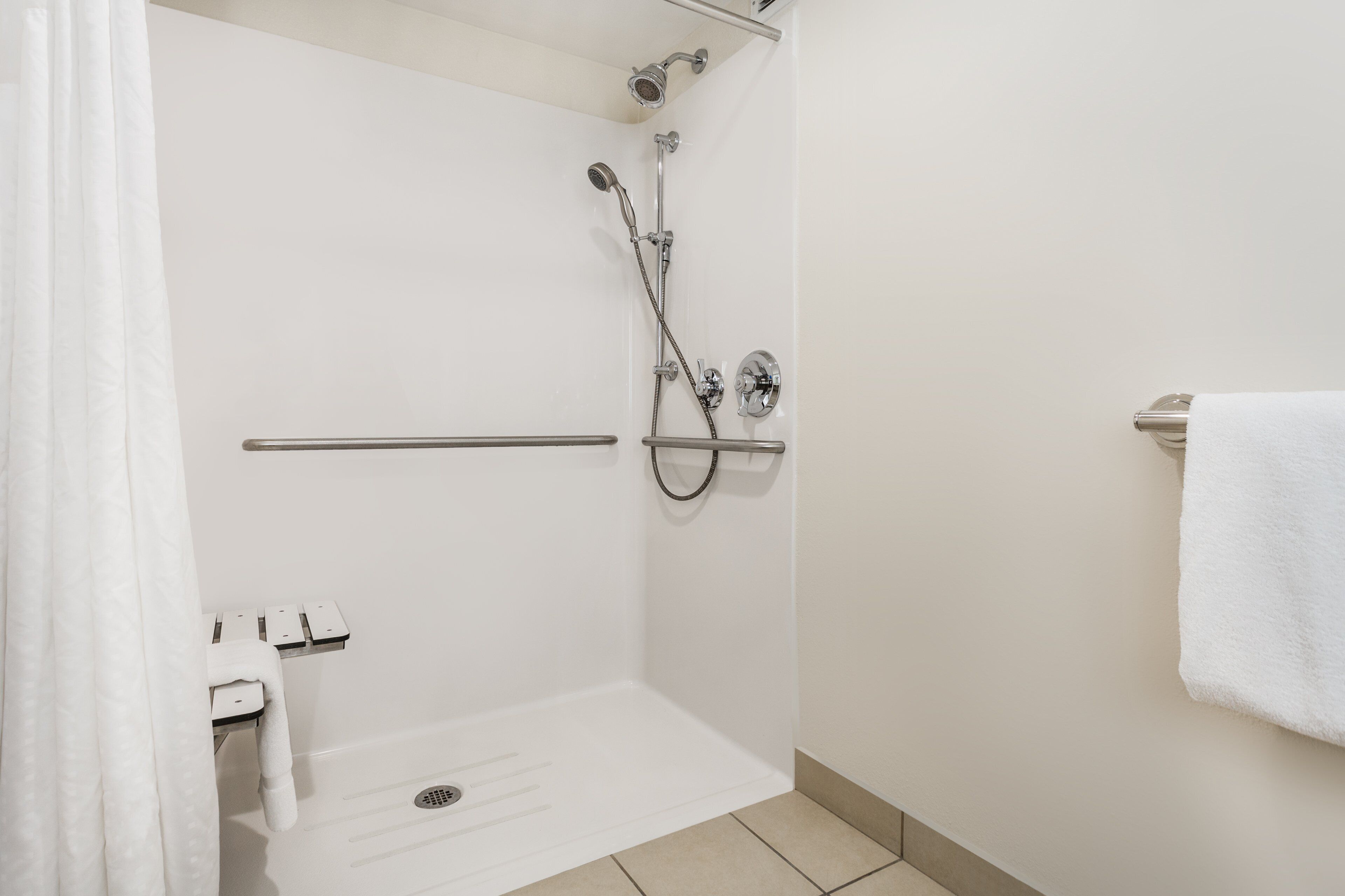 Un espacio de ducha moderno con un cabezal de ducha de mano, un grifo de pared y un perchero para toallas.