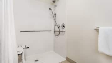 Un espacio de ducha moderno con un cabezal de ducha de mano, un grifo de pared y un perchero para toallas.