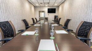 A conference room with a long table, chairs, and a television screen on the wall.