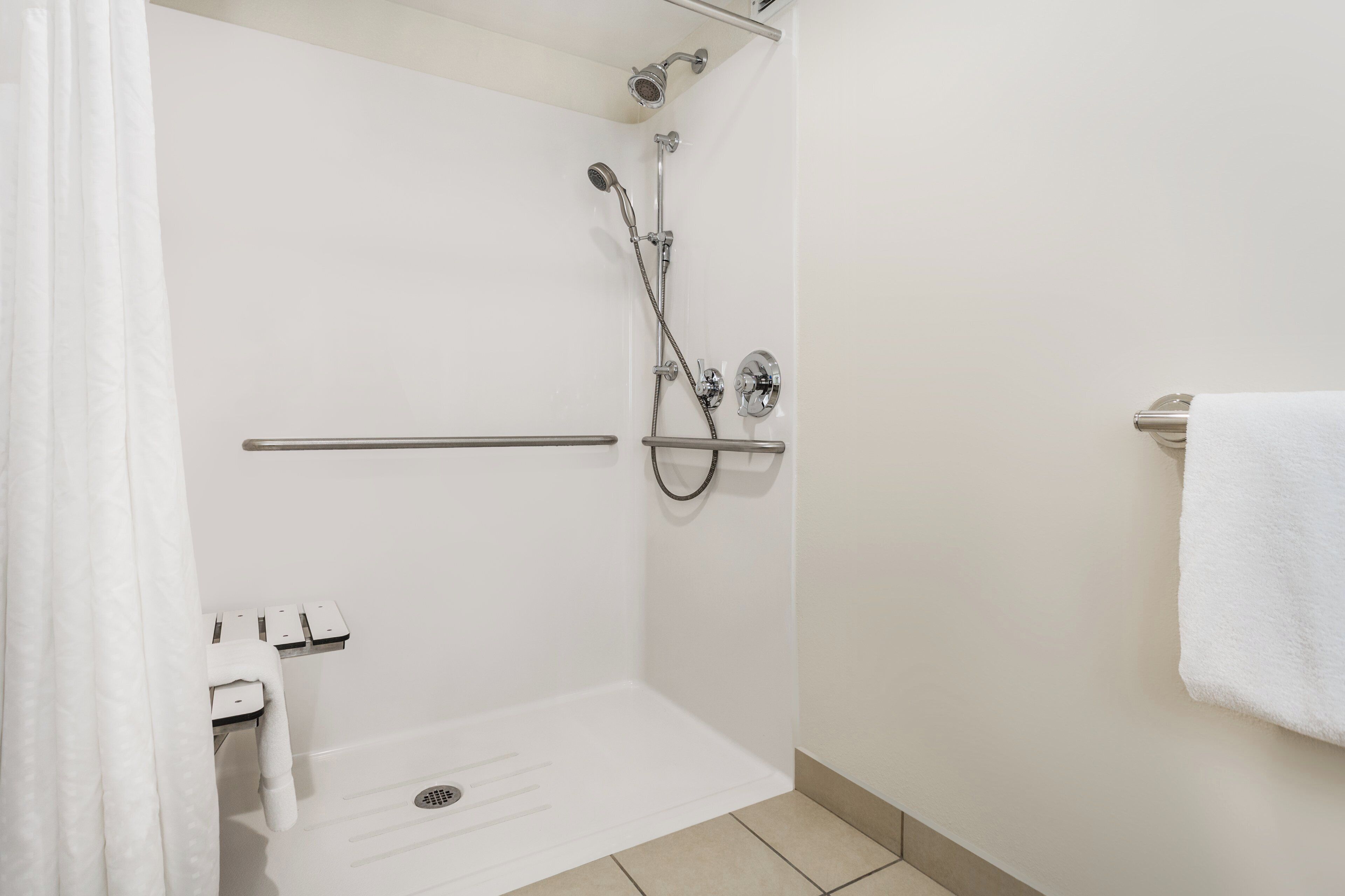 A white bathroom with a shower, a towel rack, and a toilet.