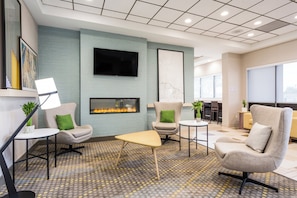 A modern lounge area with seating, a fireplace, and a flat-screen TV.