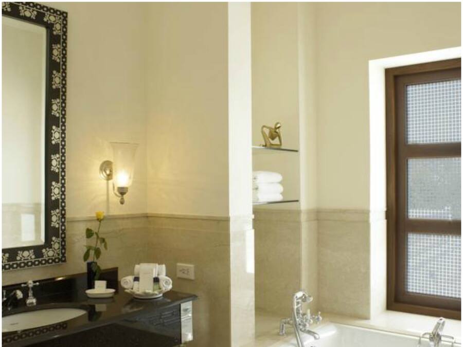 A bathroom with a large mirror, a sink, a vanity, a towel rack, and a window with blinds.