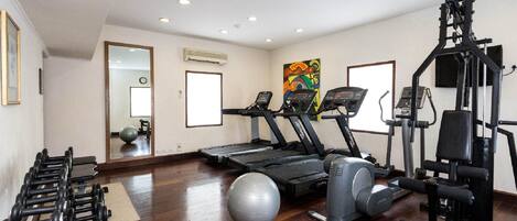 A gym with treadmills, dumbbells, and exercise balls.