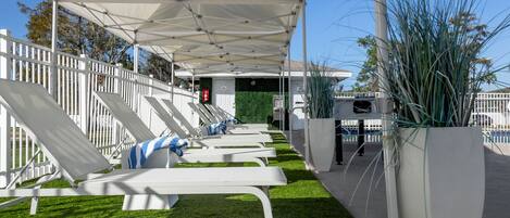 Un espacio de estar al aire libre cubierto con sillones blancos y una cerca blanca.