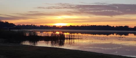 A sunset over a calm lake with a small structure in the foreground.