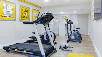 Un gimnasio con cintas de correr, elíptica y bicicleta estática.