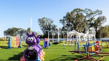 A playground with various play structures including a purple slide and a climbing frame.