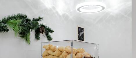 A buffet counter with various food items, including pastries and bread, and a decorative sign above.