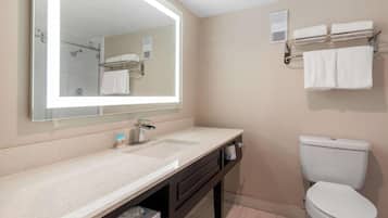 Een moderne badkamer met een grote spiegel, een wastafel, toilet en een handdoekhouder.