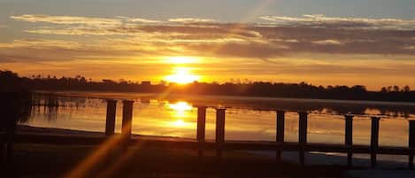 A sunset over a calm body of water with a wooden dock in the foreground.