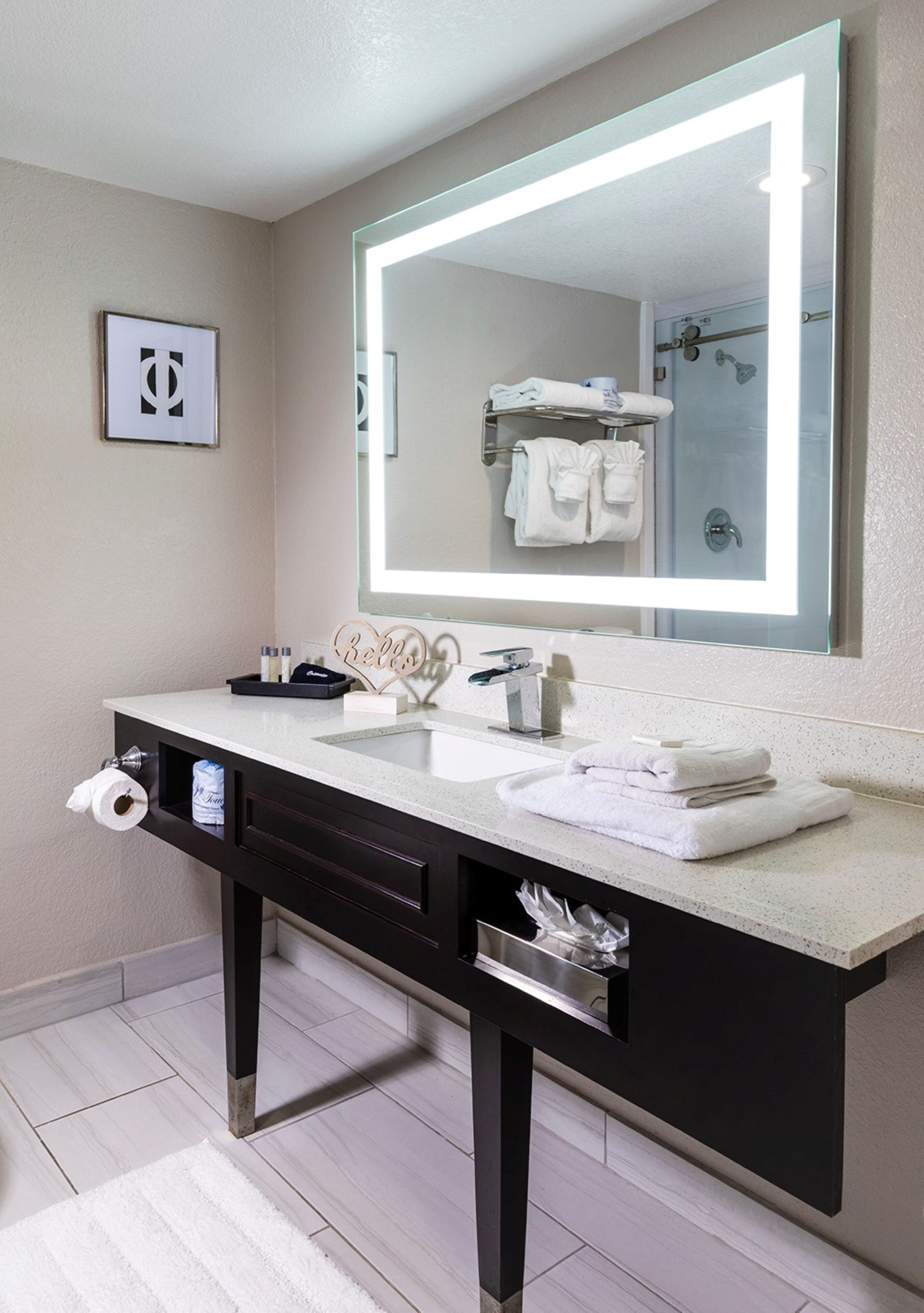 Un baño moderno con un espejo grande, dos lavamanos y un mueble de tocador con cajones.