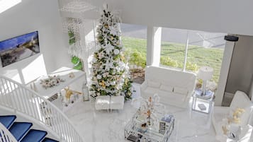 A spacious living area with a white Christmas tree, a sofa, a coffee table, and a staircase.
