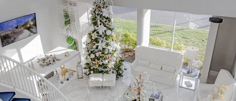 A spacious living area with a white Christmas tree, a sofa, a coffee table, and a staircase.