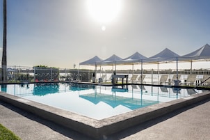 Una piscina al aire libre, sillones reclinables de piscina