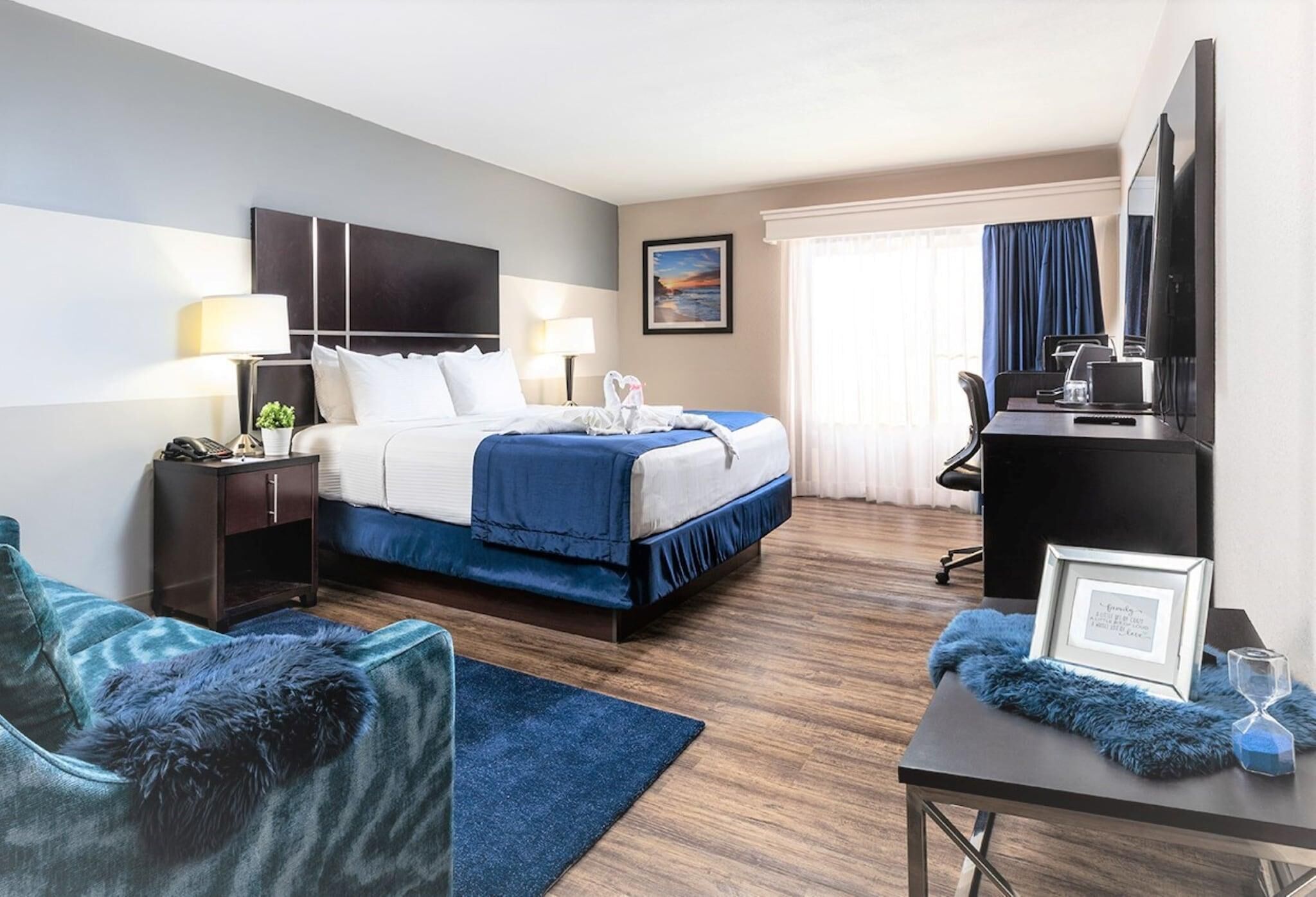 Une chambre d’hôtel comprenant un lit, un bureau avec un ordinateur, une télévision et une chaise.