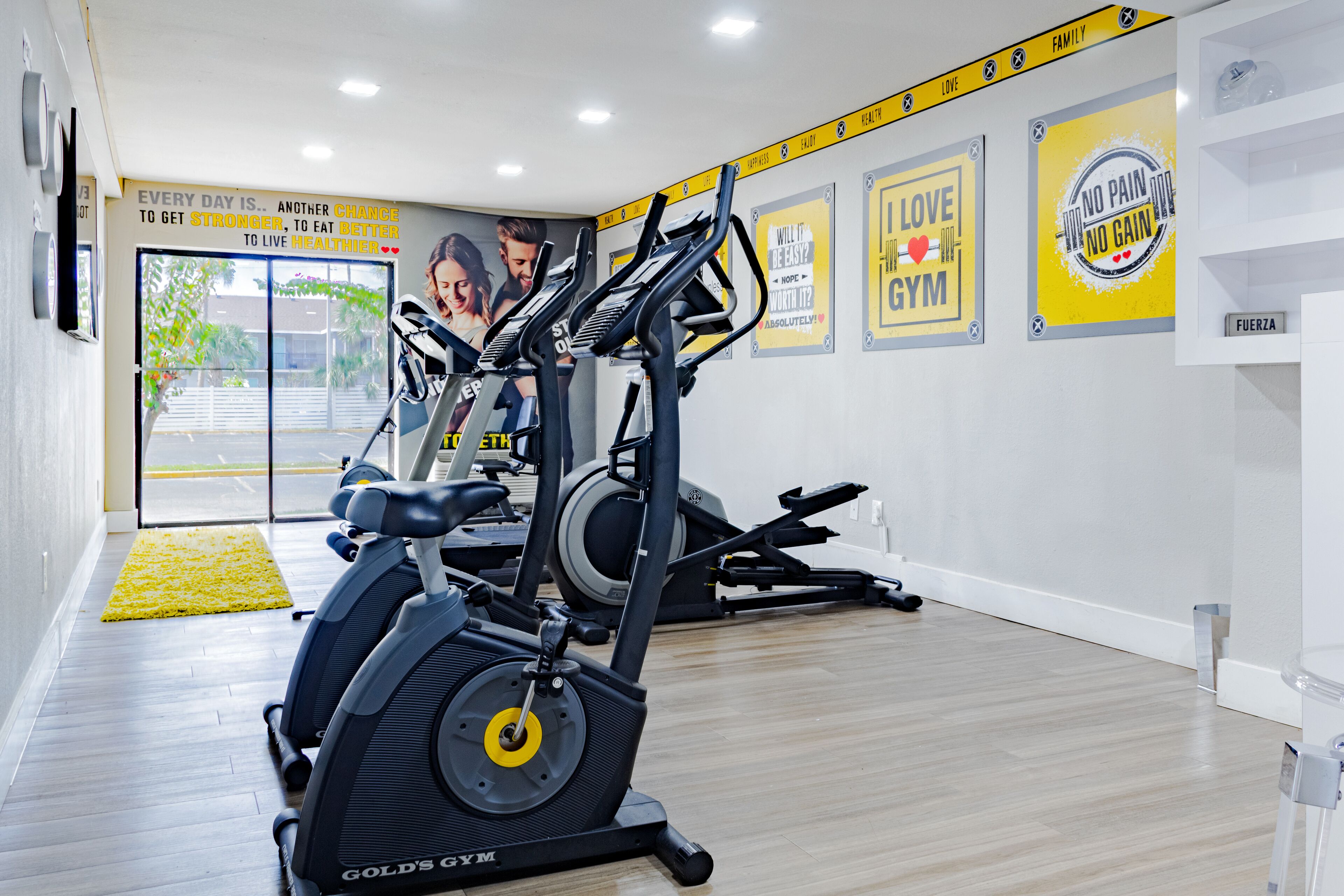 A gym with exercise equipment, motivational posters, and a yellow mat.