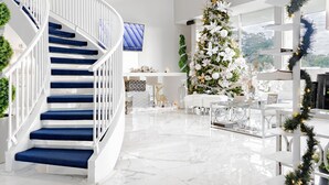 A modern interior with a white spiral staircase, a large Christmas tree, and a dining area with white furniture. - Palazzo Lakeside Hotel (Kissimmee)