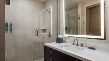 A modern bathroom with a large mirror, two sinks, and a shower.