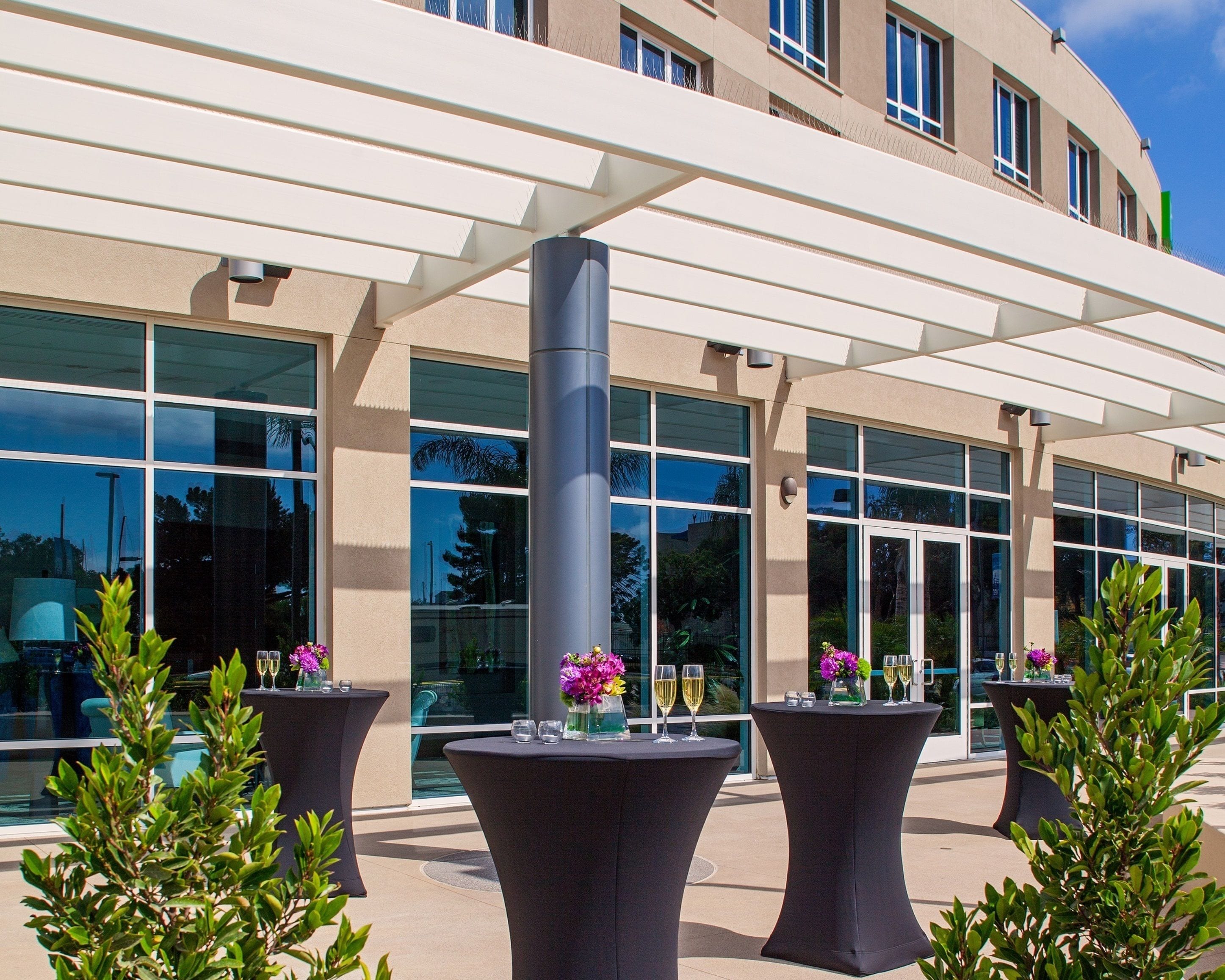 A modern building with large windows and outdoor seating areas with tables and chairs.
