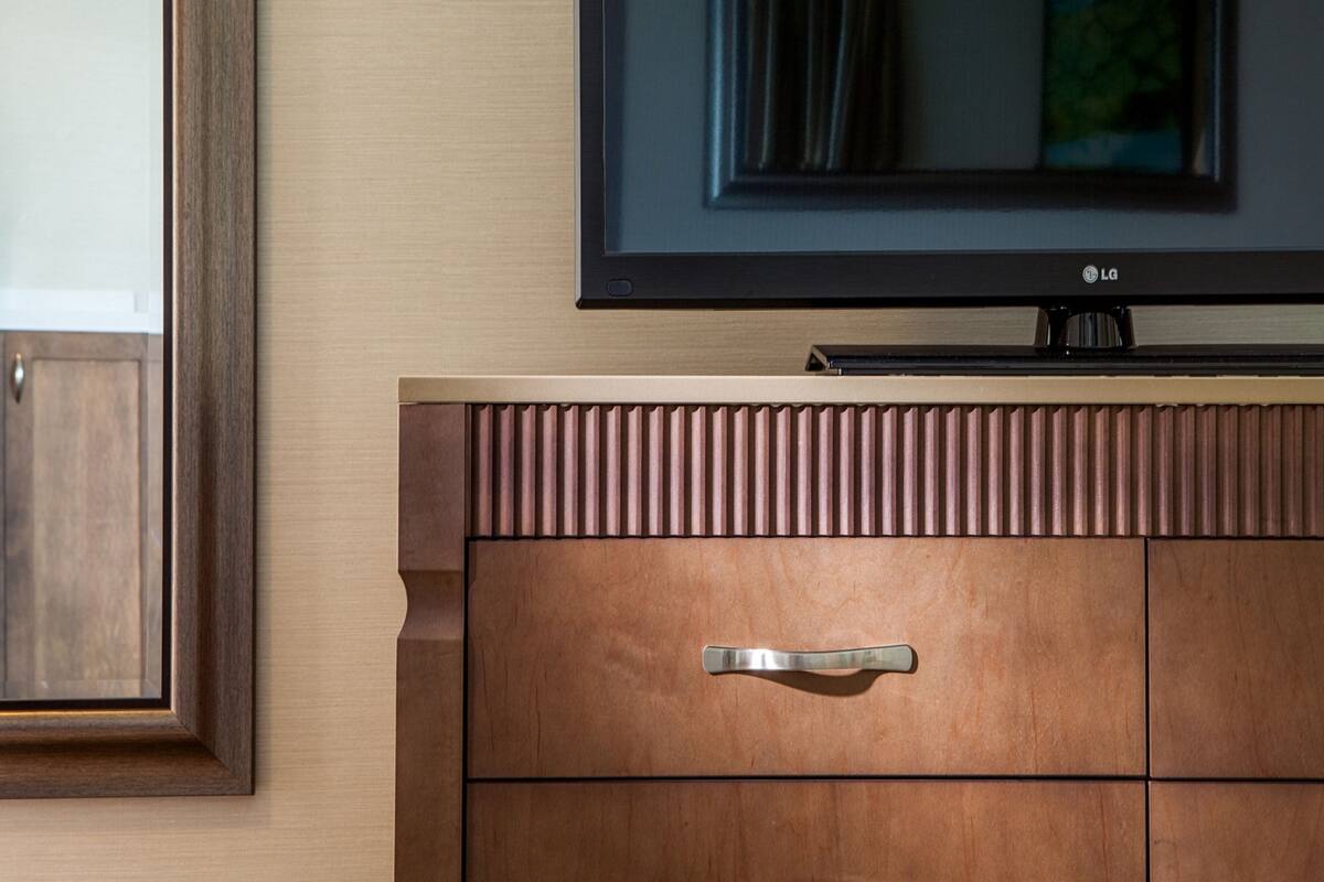 A flat-screen TV mounted on a wooden cabinet with a handle.