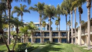 Un hôtel doté d’une cour intérieure agrémentée de palmiers, d’un terrain de golf et d’un bâtiment avec des balcons.