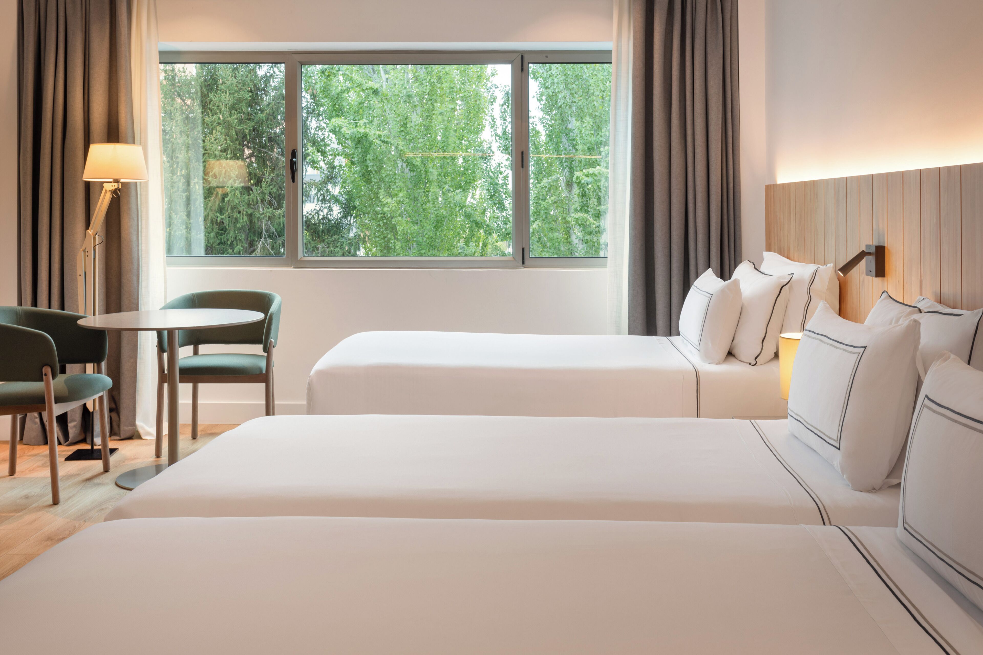 A hotel room with two beds, a desk, and a chair.